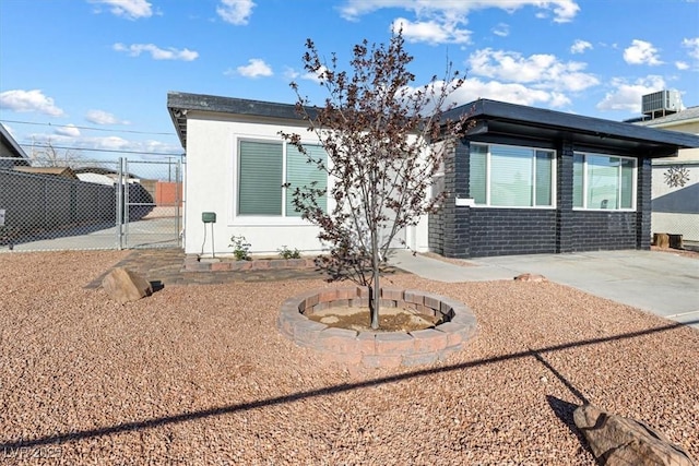 view of front of property featuring a gate, fence, and central AC