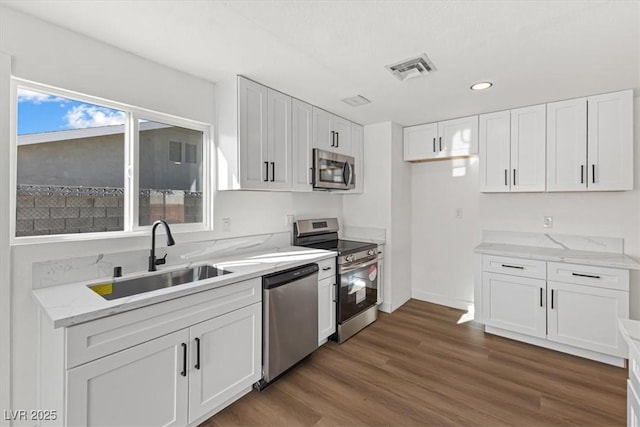 kitchen with dark wood-style floors, visible vents, a sink, white cabinets, and appliances with stainless steel finishes