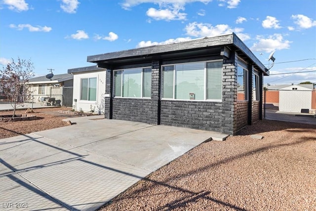 view of front of home with a patio area, brick siding, and fence