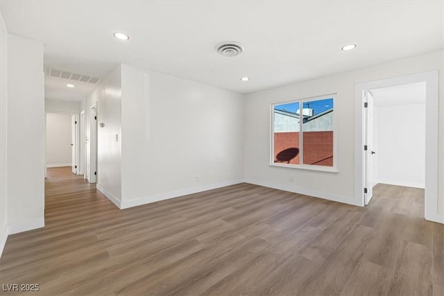 spare room featuring recessed lighting, wood finished floors, visible vents, and baseboards