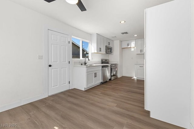 kitchen with white cabinetry, light countertops, wood finished floors, and appliances with stainless steel finishes