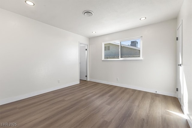 empty room with recessed lighting, wood finished floors, and baseboards