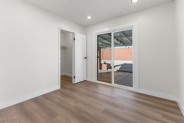 unfurnished bedroom featuring access to exterior, recessed lighting, baseboards, and wood finished floors