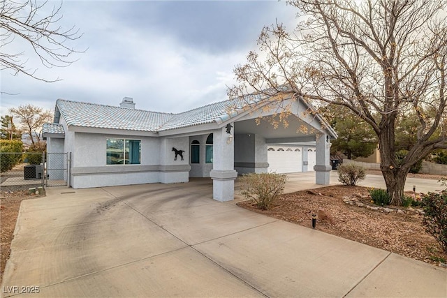 view of front of home featuring an attached garage, central AC, stucco siding, concrete driveway, and a tiled roof