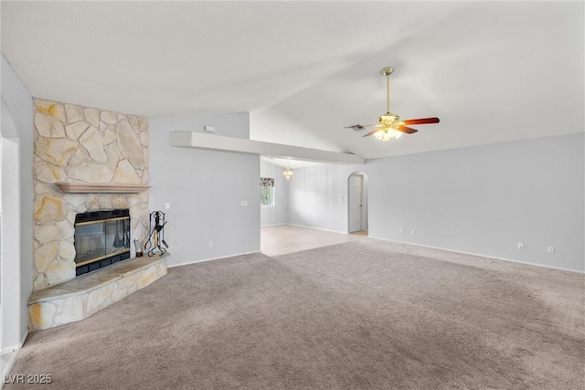 unfurnished living room with lofted ceiling, a stone fireplace, ceiling fan, and carpet flooring