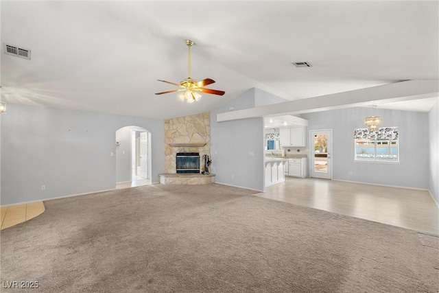 unfurnished living room featuring light carpet, visible vents, a fireplace, and lofted ceiling