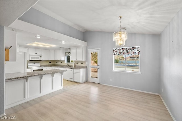 kitchen featuring white appliances, light stone counters, a peninsula, light wood-style flooring, and white cabinets