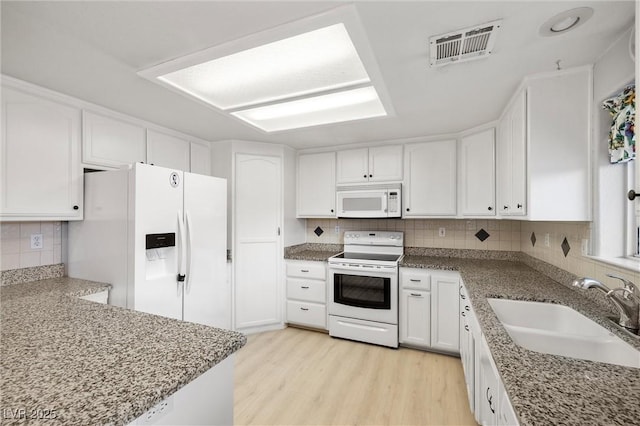 kitchen featuring visible vents, a sink, white appliances, white cabinets, and light wood finished floors