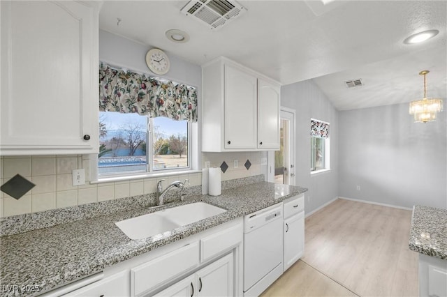 kitchen featuring a sink, backsplash, visible vents, and white dishwasher