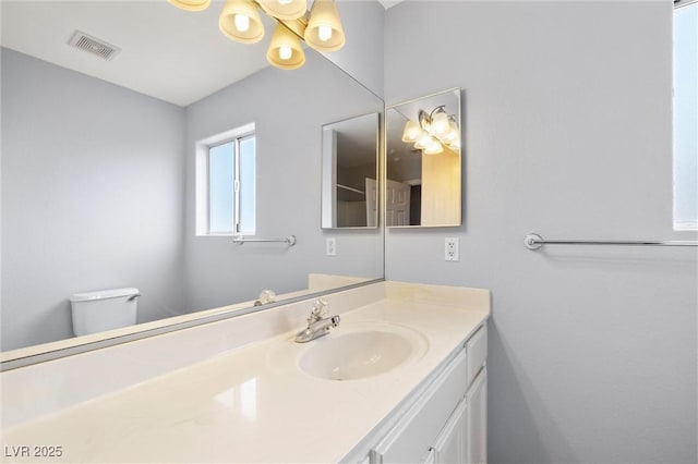 bathroom featuring visible vents, toilet, and vanity