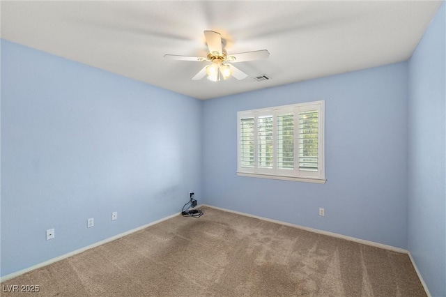 carpeted spare room with visible vents, baseboards, and a ceiling fan