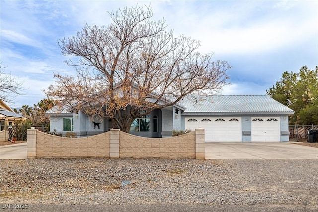 view of front of house with an attached garage, stucco siding, concrete driveway, a fenced front yard, and a tiled roof