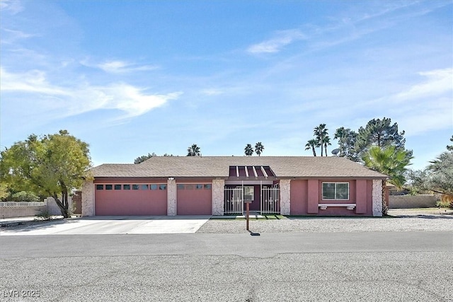 ranch-style house with an attached garage, concrete driveway, fence, and stucco siding