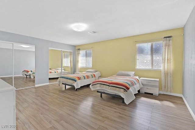 bedroom featuring multiple closets, wood finished floors, and baseboards