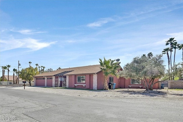 ranch-style home featuring a garage, driveway, and fence