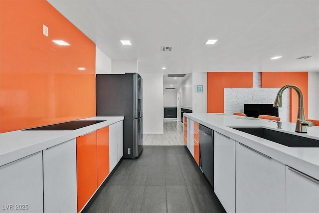 kitchen featuring a sink, black appliances, light countertops, a fireplace, and recessed lighting