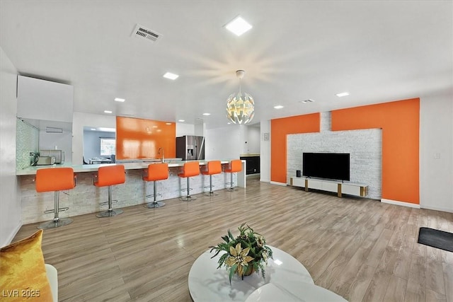 living room with a chandelier, light wood-style floors, baseboards, and recessed lighting