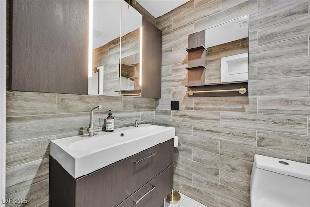 bathroom with tile walls, toilet, and vanity