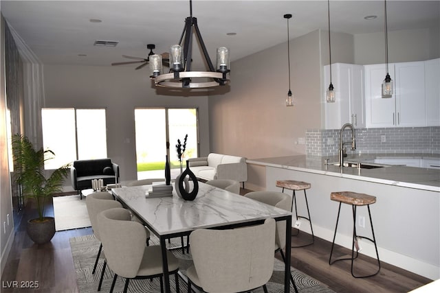 dining area with dark wood finished floors, an inviting chandelier, and visible vents