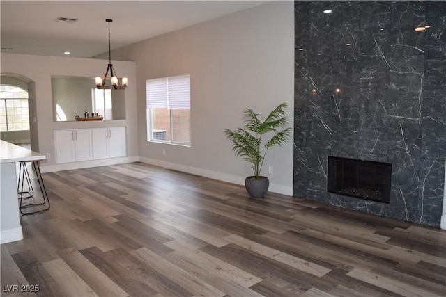 unfurnished living room featuring arched walkways, visible vents, and wood finished floors