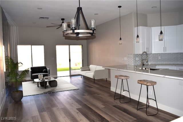 kitchen featuring visible vents, dark wood-type flooring, a sink, open floor plan, and white cabinets