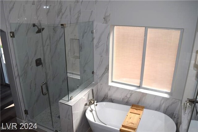 bathroom featuring a marble finish shower and a freestanding bath