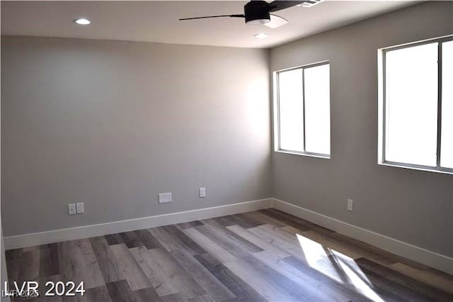 empty room with baseboards, plenty of natural light, wood finished floors, and a ceiling fan