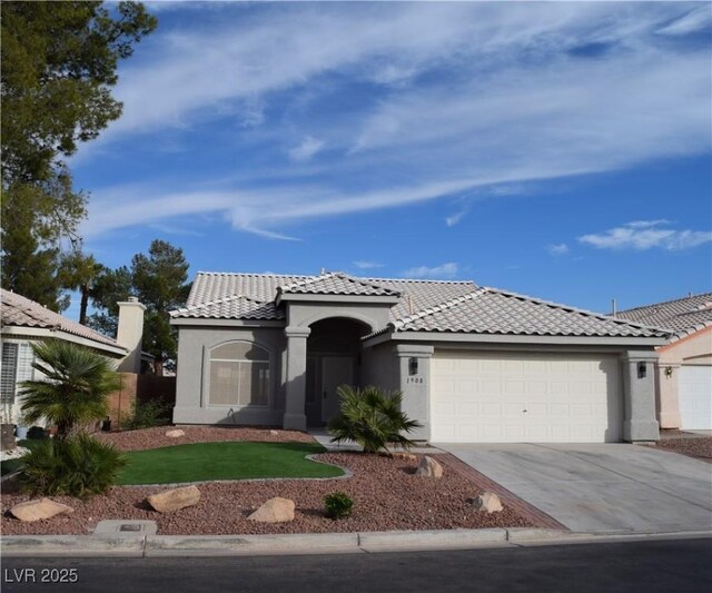 mediterranean / spanish house featuring a tiled roof, stucco siding, driveway, and an attached garage