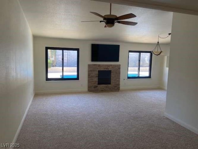 unfurnished living room with light colored carpet, a fireplace, a textured ceiling, and baseboards