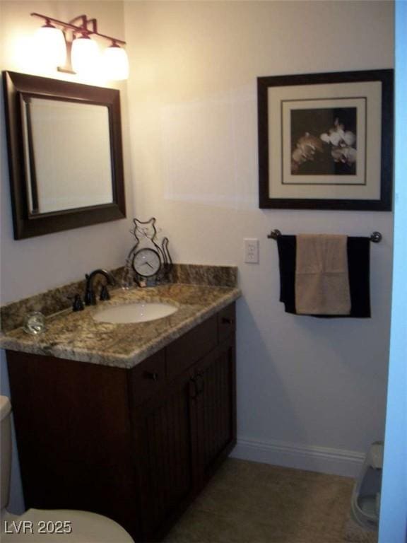 half bathroom with toilet, vanity, and baseboards