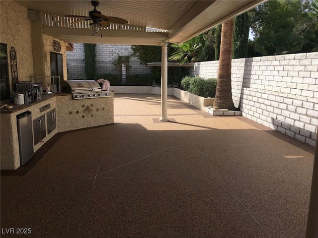 view of patio featuring area for grilling, a ceiling fan, fence, and an outdoor kitchen