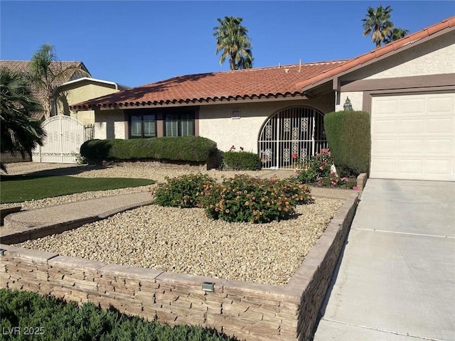 view of front of house featuring a tiled roof, a gate, an attached garage, and stucco siding