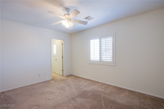 spare room with visible vents, light colored carpet, baseboards, and a ceiling fan