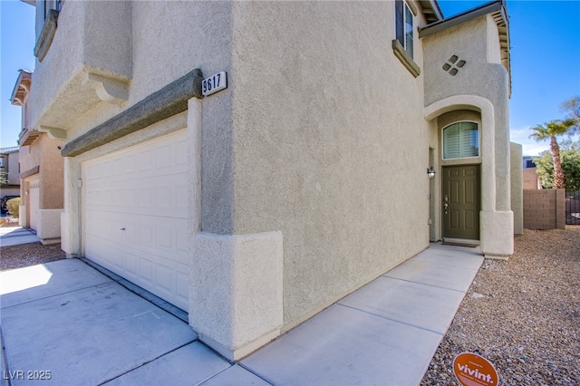 view of exterior entry with stucco siding and fence