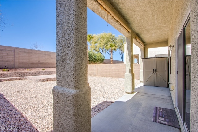 view of patio with a storage shed, an outbuilding, and a fenced backyard