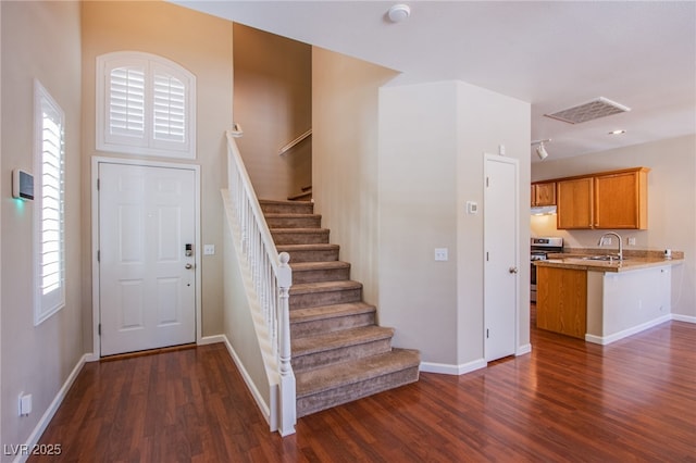 entryway featuring stairs, dark wood-type flooring, and baseboards