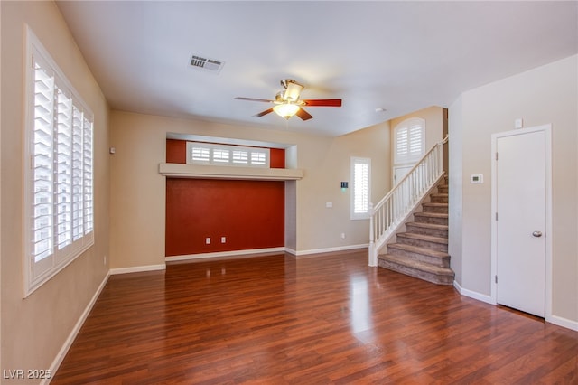 unfurnished living room featuring visible vents, baseboards, wood finished floors, and stairs