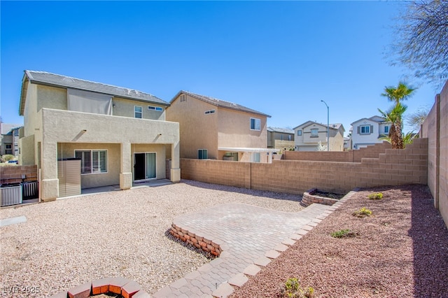 rear view of house featuring a patio area, stucco siding, and a fenced backyard