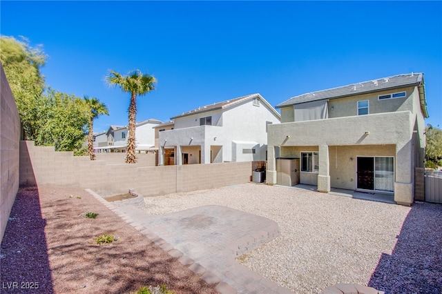 rear view of house featuring stucco siding, a fenced backyard, and a patio area