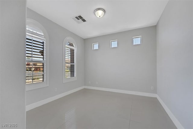 tiled empty room featuring baseboards and visible vents