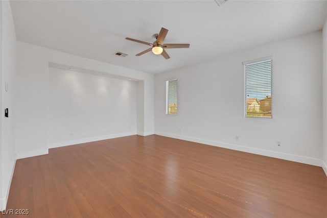 empty room featuring visible vents, baseboards, wood finished floors, and a ceiling fan