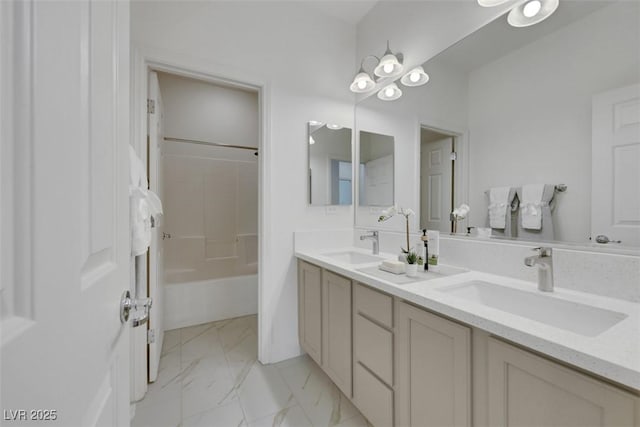 full bath with a sink, marble finish floor, bathtub / shower combination, and double vanity