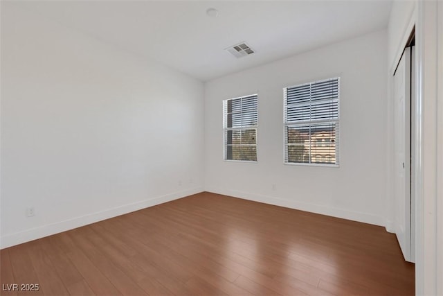 spare room featuring visible vents, baseboards, and wood finished floors