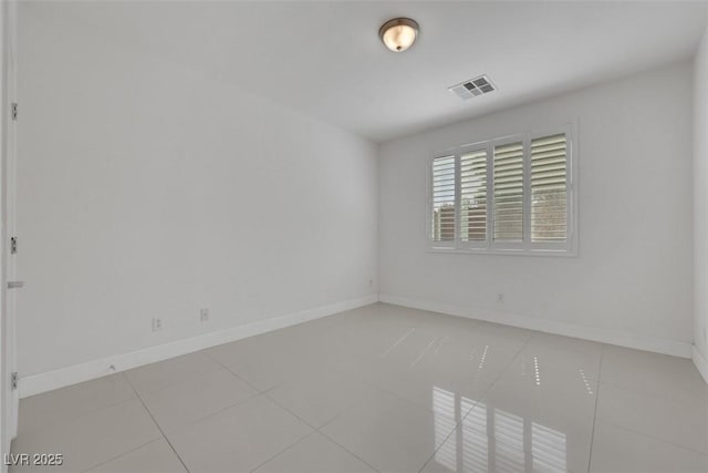 empty room with light tile patterned floors, visible vents, and baseboards