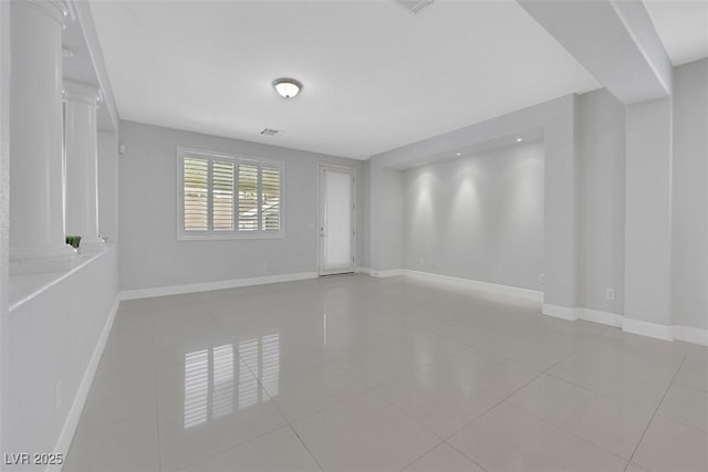 tiled spare room with visible vents, baseboards, and decorative columns