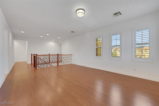 spare room featuring recessed lighting, wood finished floors, visible vents, and baseboards