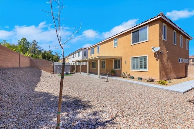 rear view of house featuring stucco siding, a patio, a tile roof, and a fenced backyard