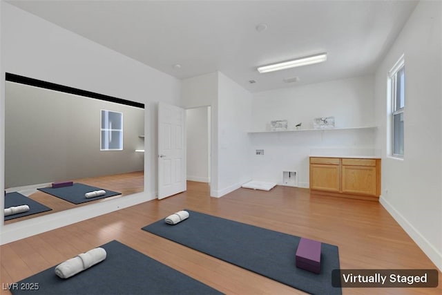 exercise area with baseboards and light wood-style floors