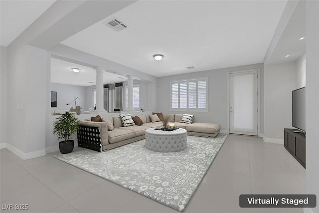 living room with decorative columns, baseboards, visible vents, and light tile patterned flooring