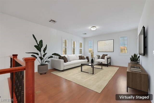 living room with visible vents, baseboards, and wood finished floors